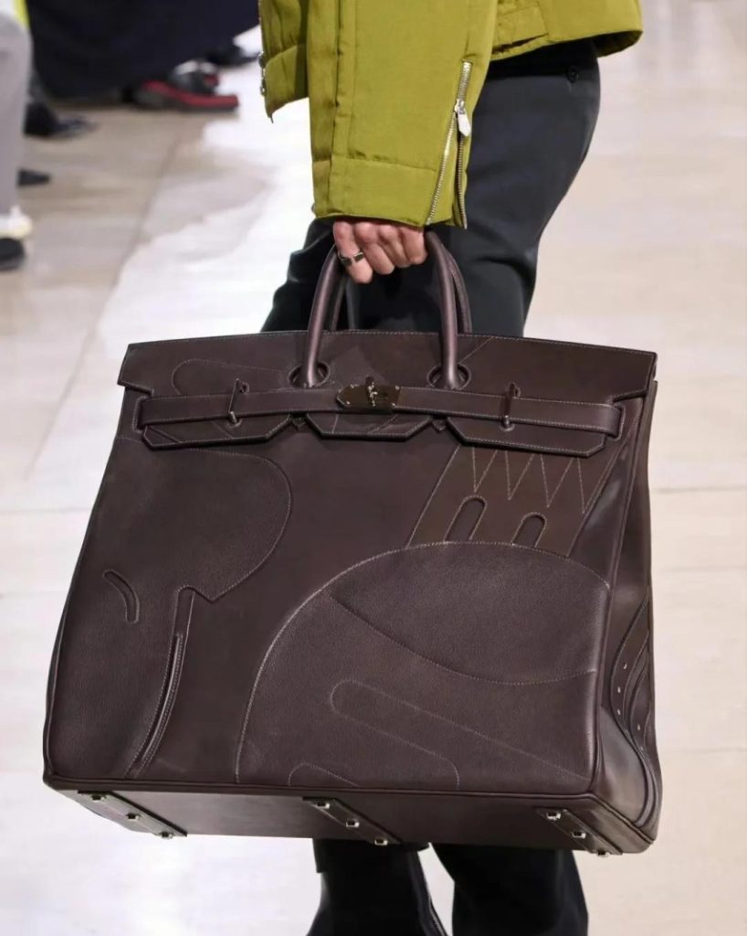 A person holding the brown Hermès HAC en Selle bag