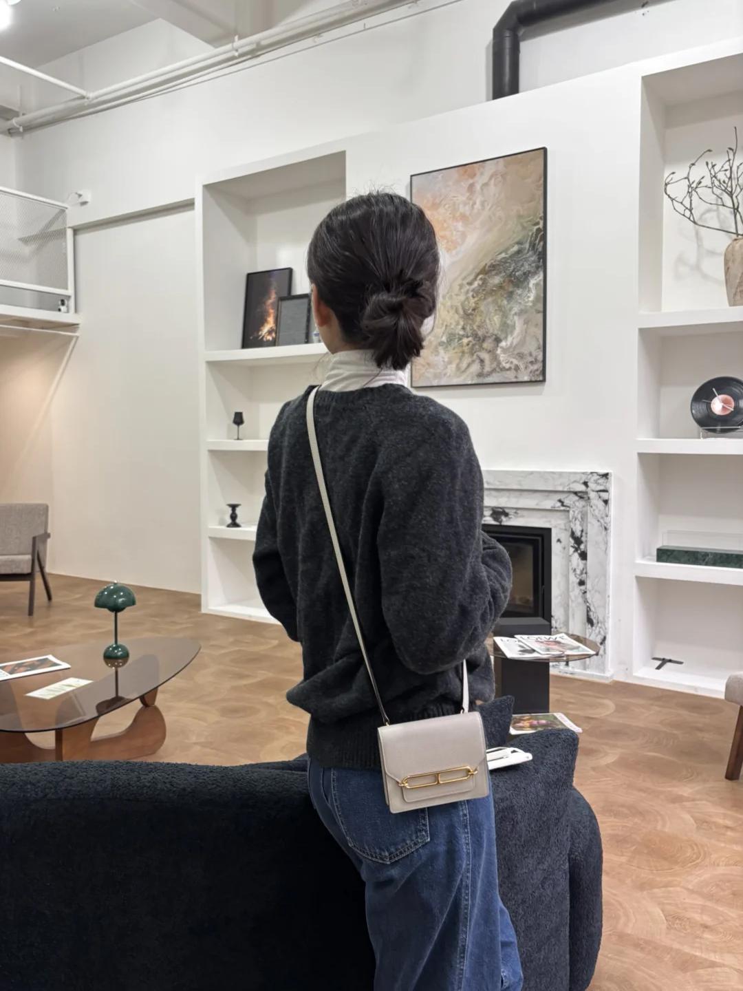 A woman wearing a Hermès Roulis Mini bag in creamy white as a crossbody