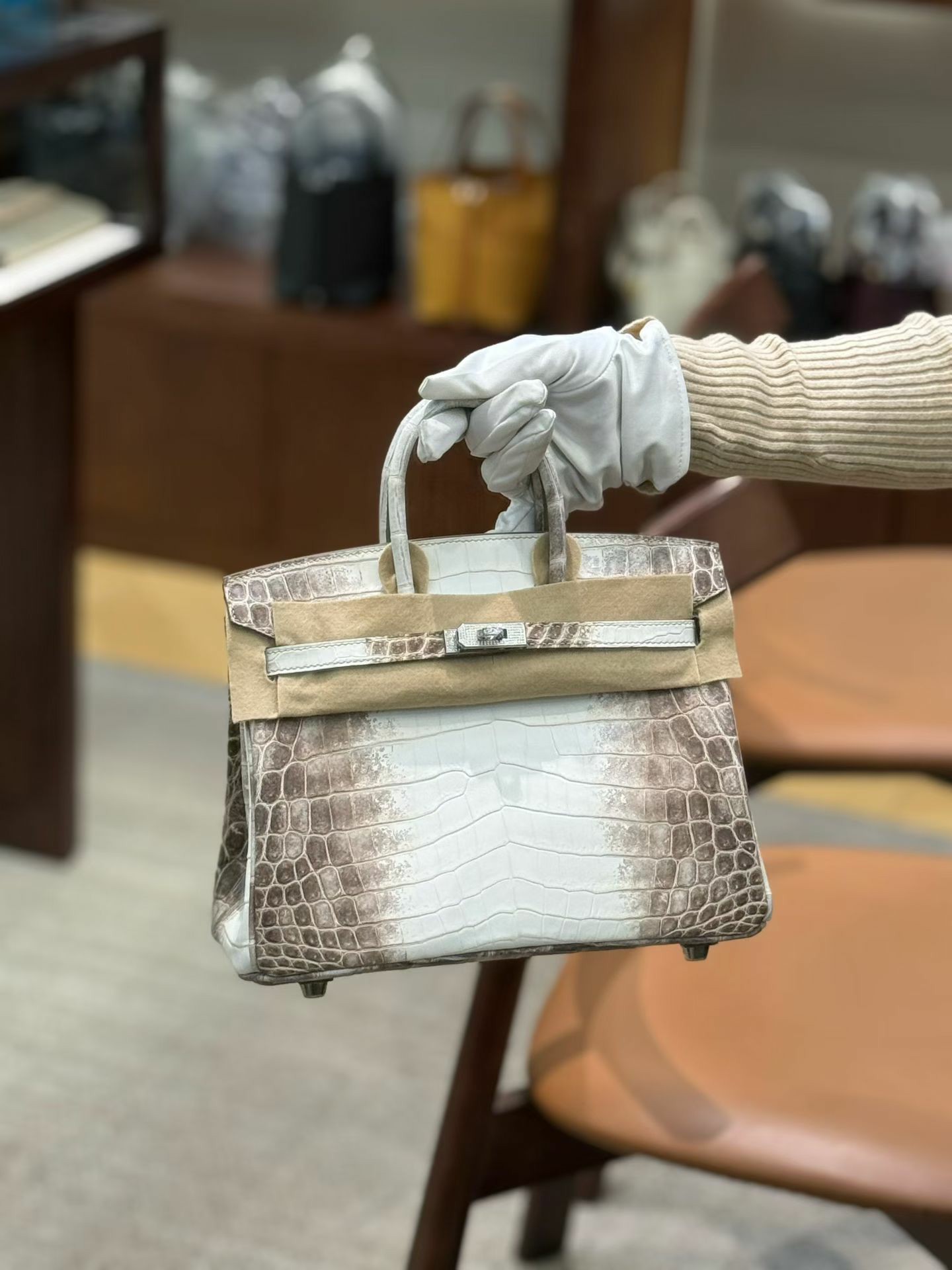 A bespoke Himalayan Birkin 25 (HCP Nile Croc) with custom diamond hardware is held with a white glove