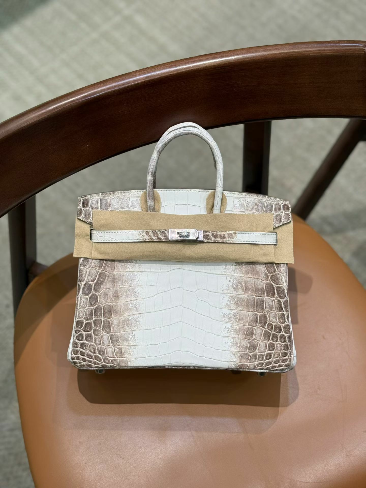 An exquisite 25cm Himalayan Birkin with custom diamond hardware is displayed on a leather chair