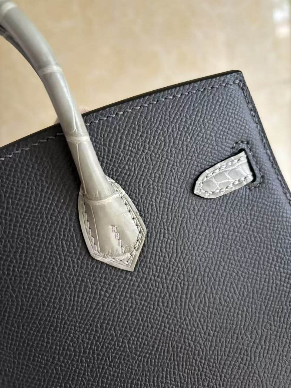 A macro close-up of the right corner of the Faubourg Birkin, focusing on the consistent edge painting and the perfect tension of the black stitching.