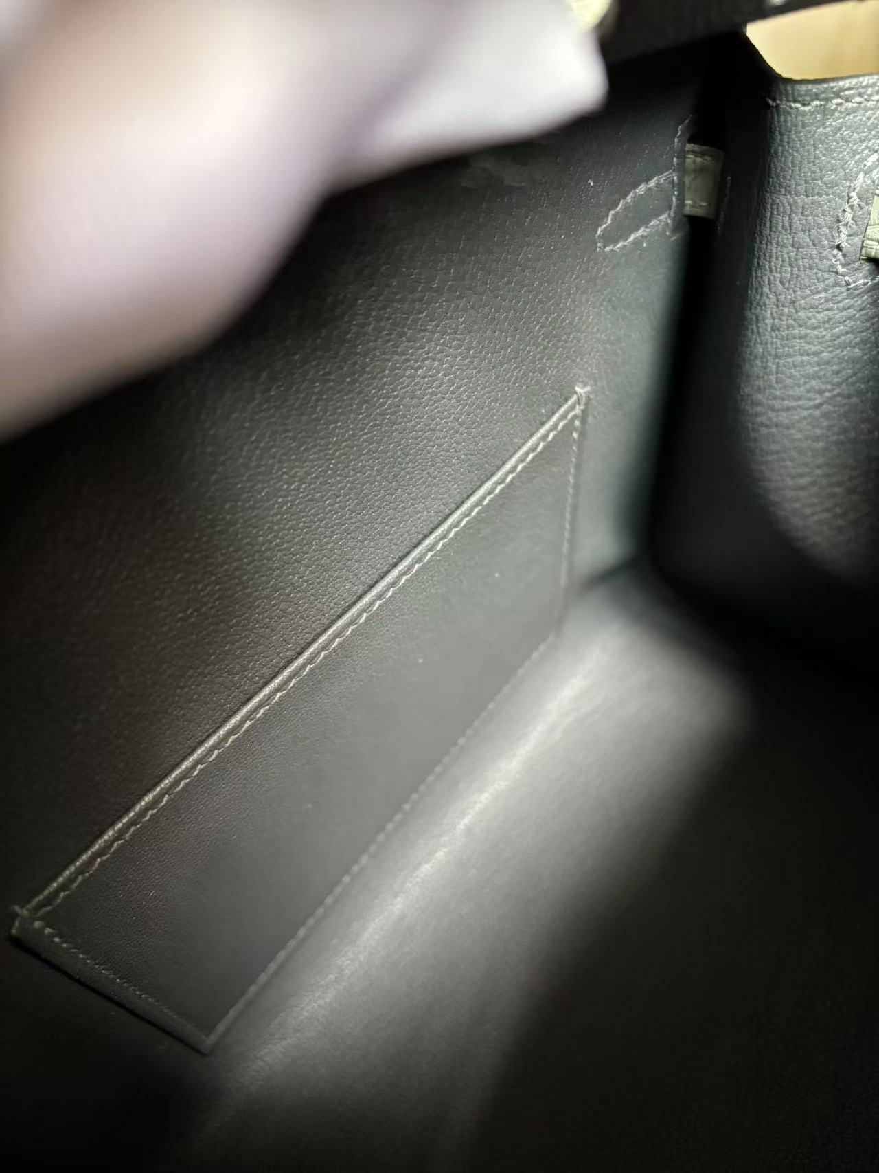 Inside view of the Faubourg Birkin, highlighting the smooth Gris Misty Chèvre lining and the neatly stitched internal slip pocket.