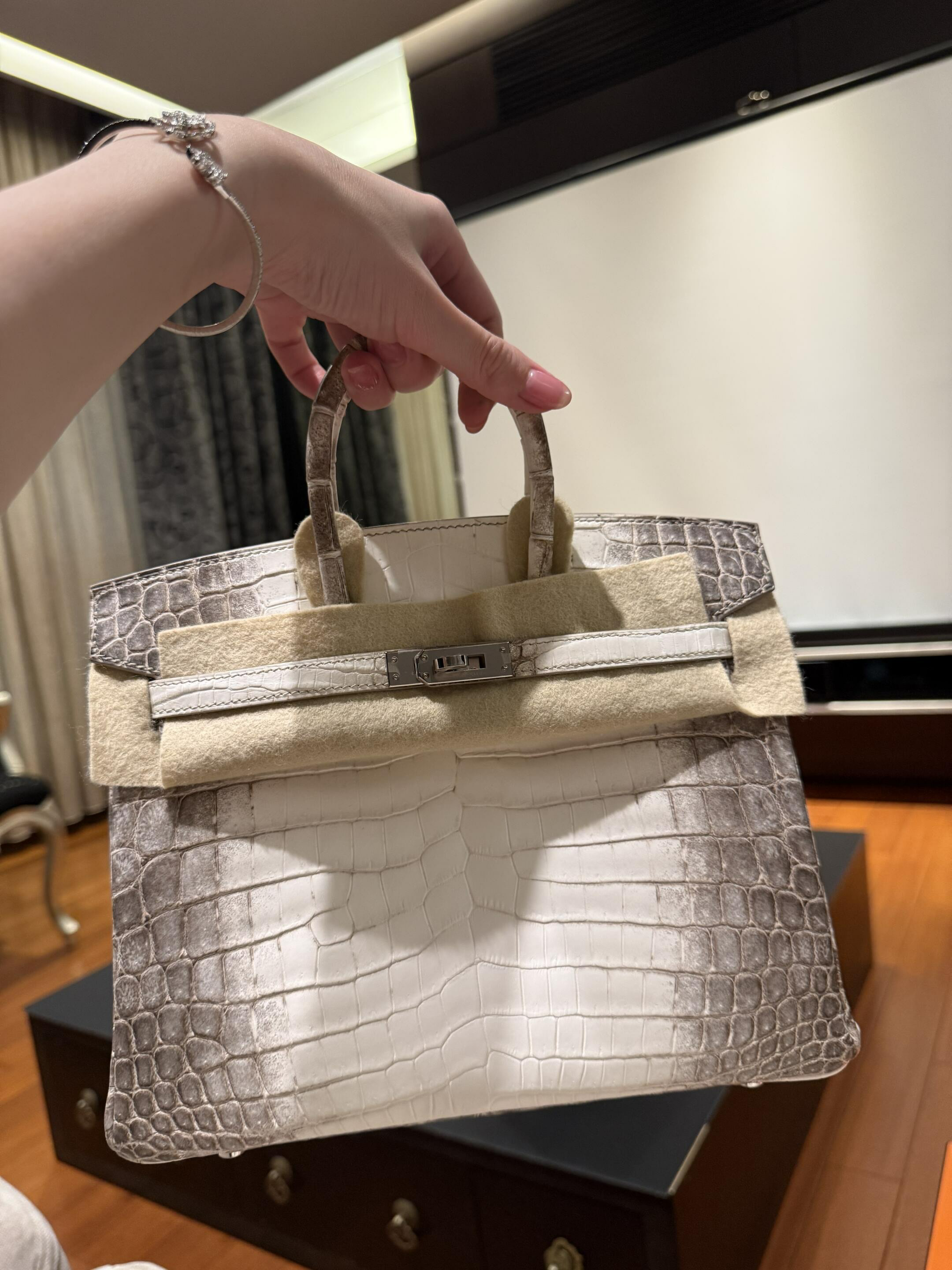 A customer holding an Hermes Himalayan Birkin 25, showing the exquisite himalayan croc Birkin texture.