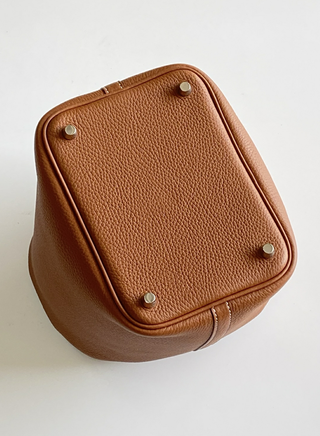Direct bottom view of the Gold Picotin Hermes style bag, highlighting the structured symmetry and neat leather seams.