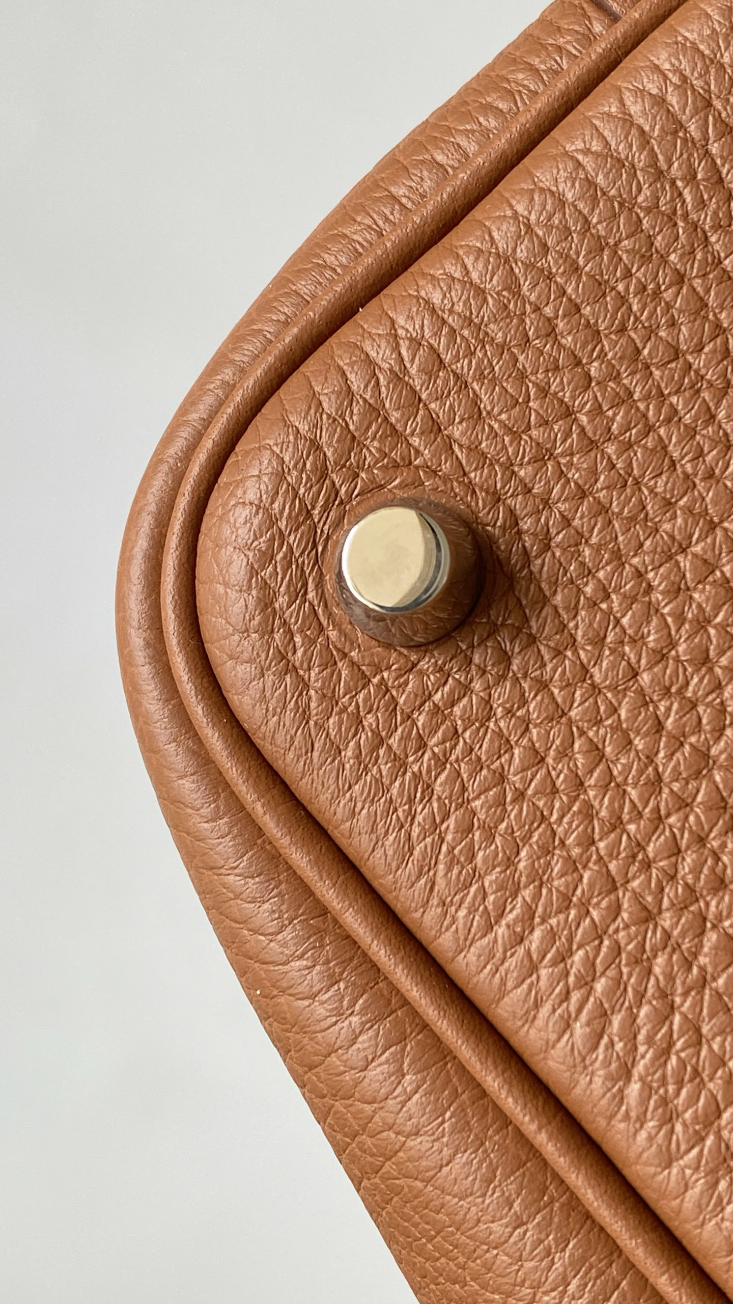 Corner close-up of a Picotin 18 bag in Gold leather, featuring a precisely centered Palladium base stud.
