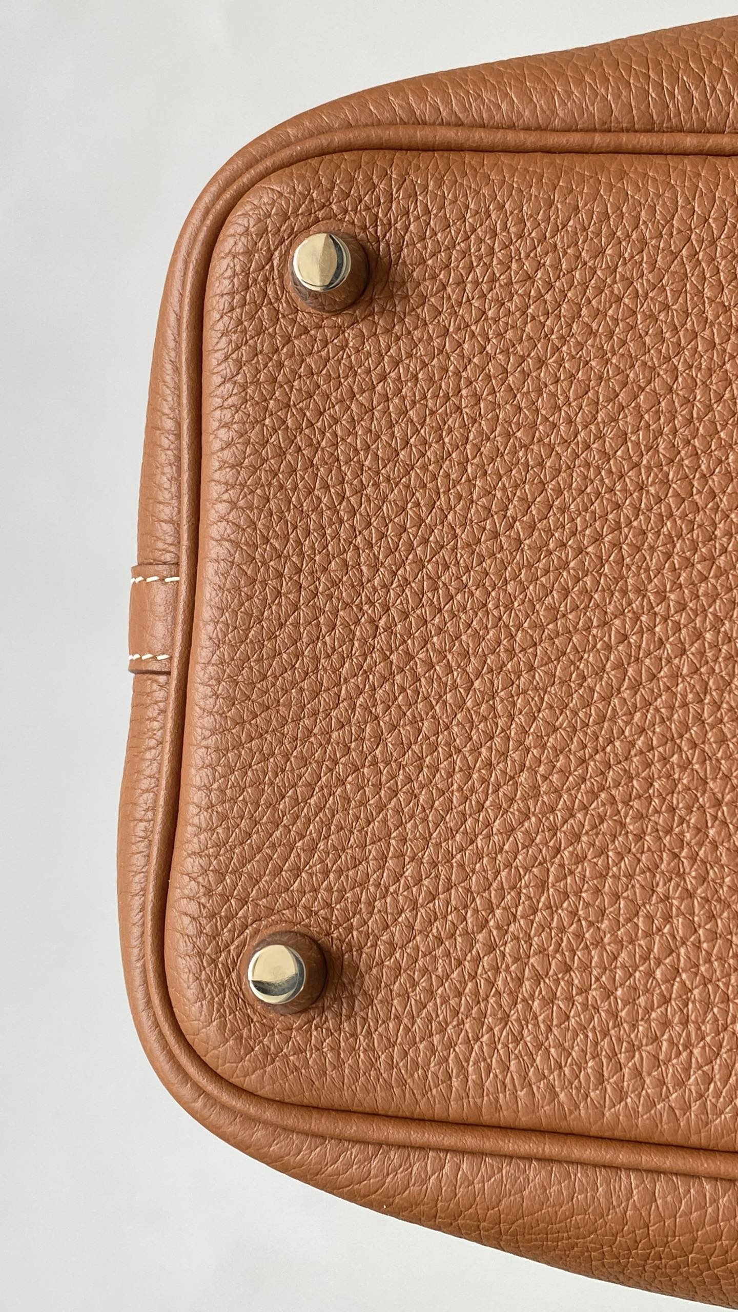 Bottom close-up of a Gold leather Picotin, showing two neatly installed Palladium base studs with minimal indentation.