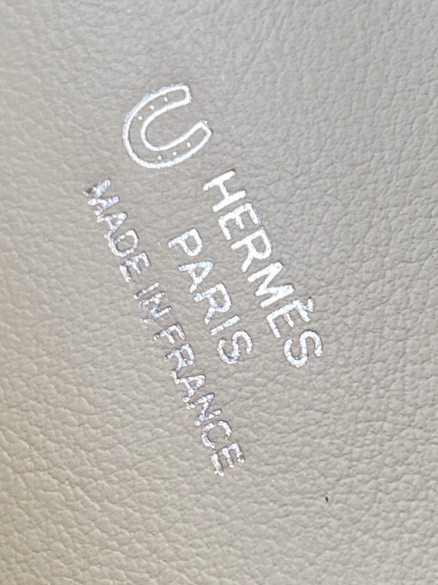 Close-up of the horseshoe stamp (HSS) with silver foiling on the interior lining of the Hermès Kelly Pochette.