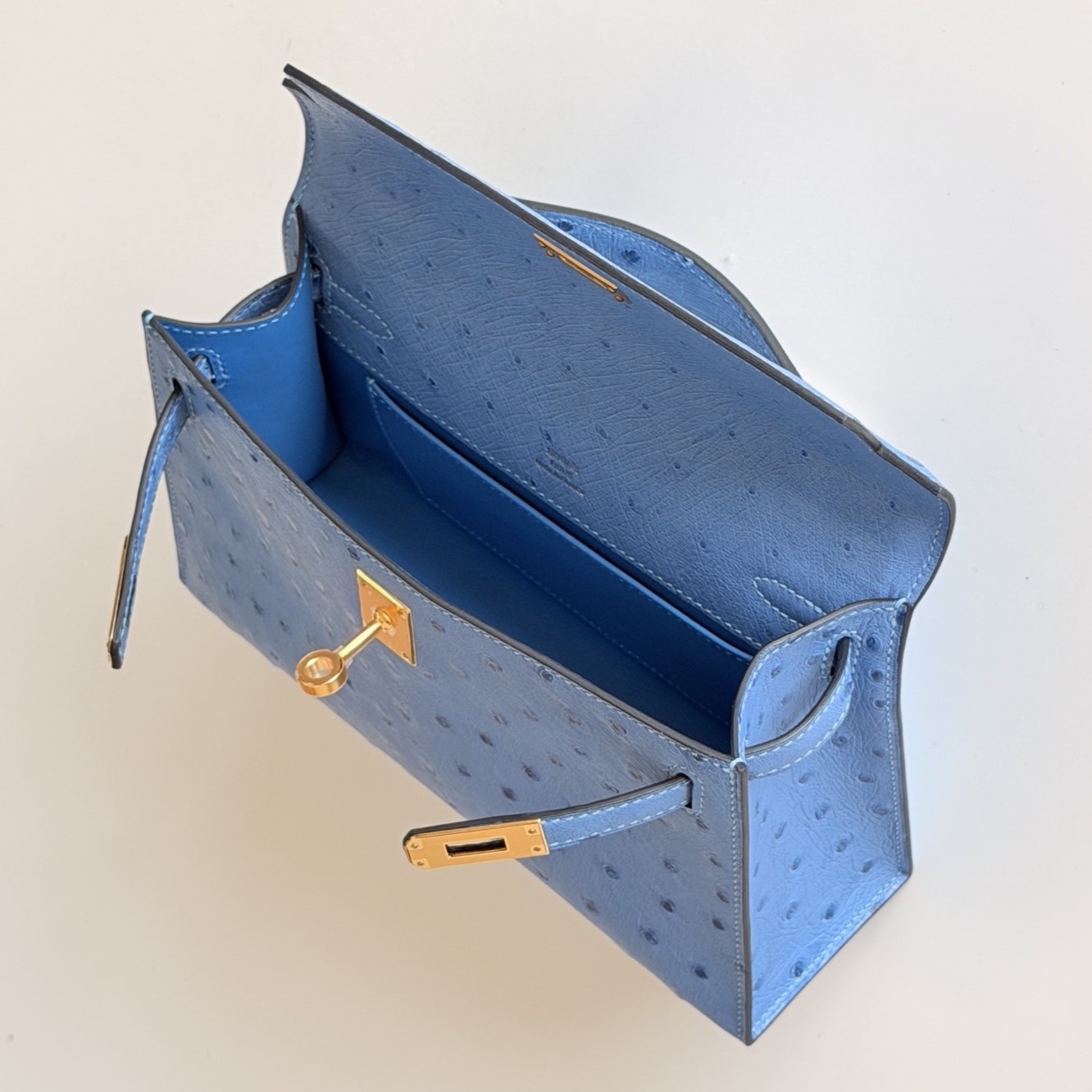 Interior compartment view of the hermes kelly pochette clutch in blue ostrich skin.