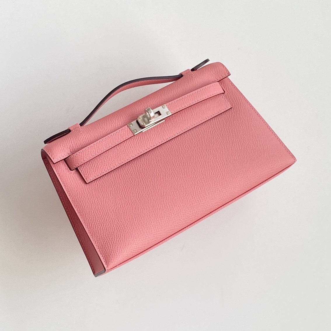 A pink Epsom leather kelly pochette hermes shown from the front