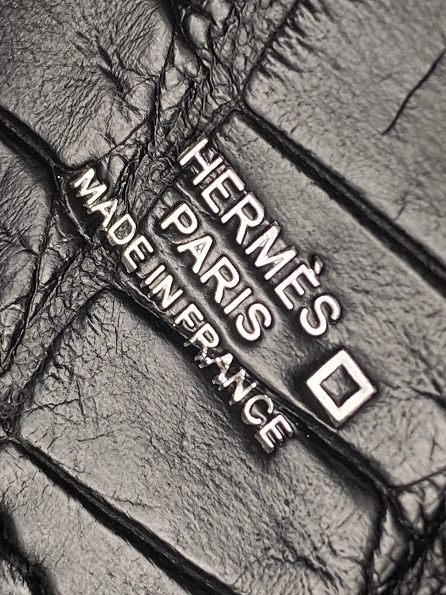 Close-up of the Hermès Kelly Pochette square stamp (☐)