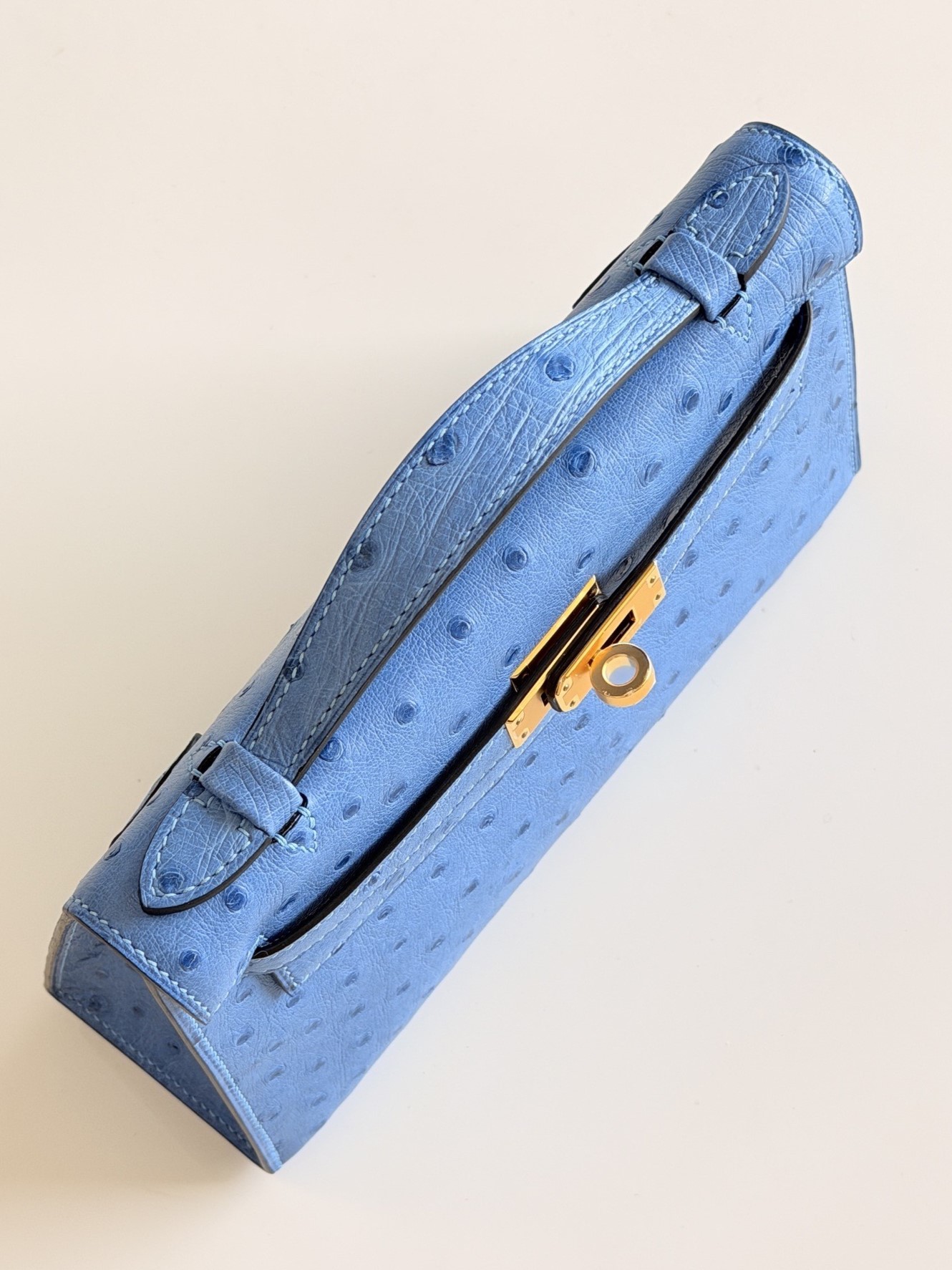 Top-down view of a hermes kelly pochette in blue ostrich.