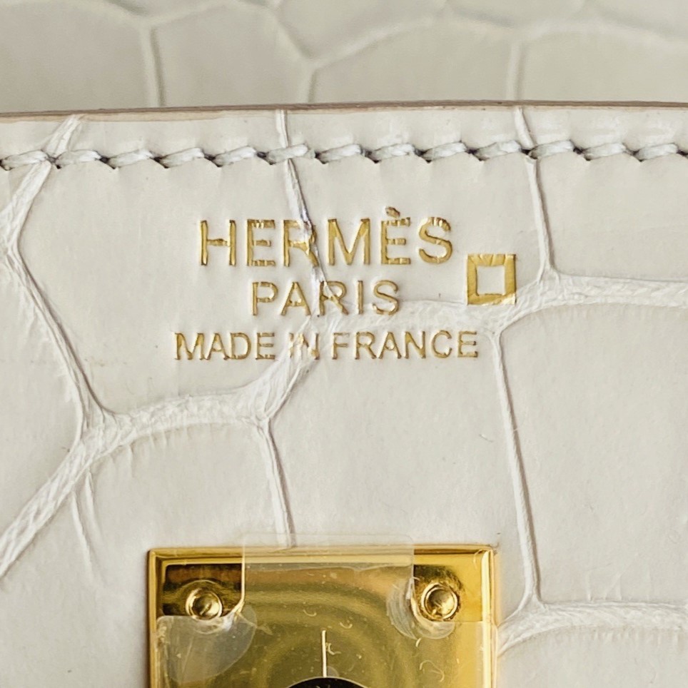 Close-up of the gold foil "Hermès Paris Made in France" stamp on a Beton alligator Birkin bag.