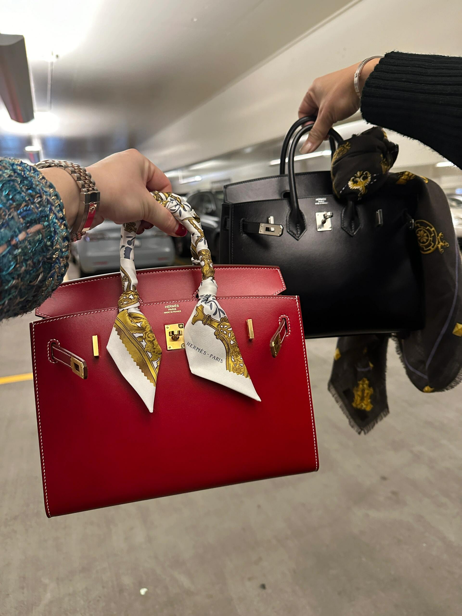 Side-by-side comparison of a red Birkin with a Twilly scarf and a classic black Birkin