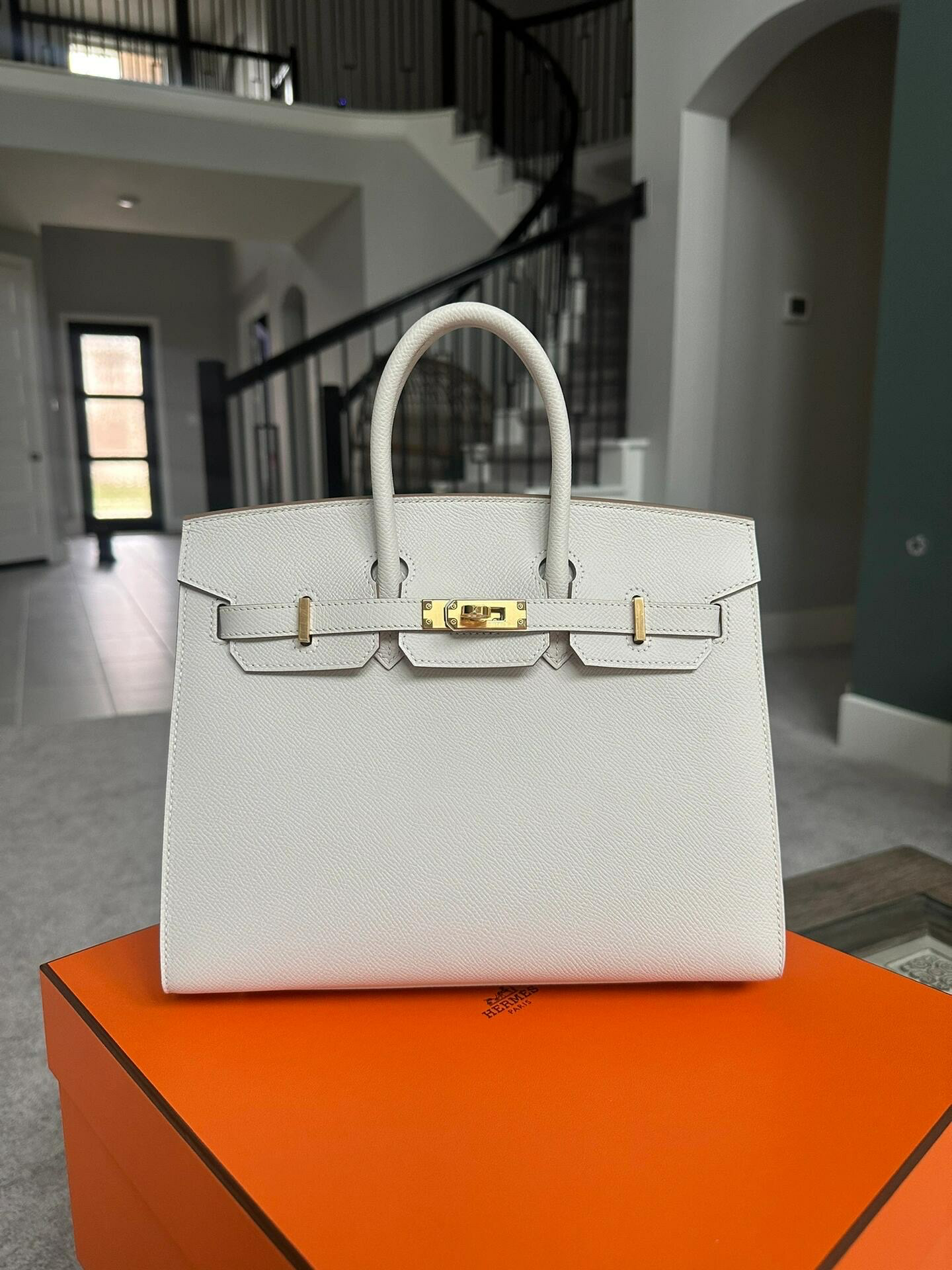 Front view of an elegant white Birkin handbag with gold hardware